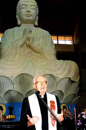 Fr. William McCarthy preaching before a Buddhist statue